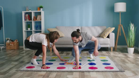 Young Man and Woman Play Twister Game at Home alt