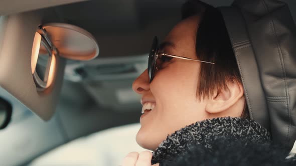 Gorgeous Caucasian Woman with Brown Hair and Toothy Smile Sitting in a Car alt