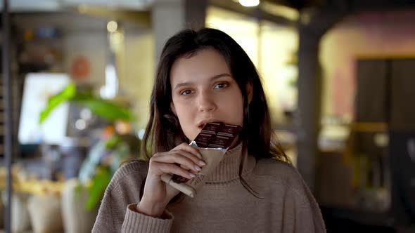 Beautiful Young Woman Eating Dark Chocolate Bar