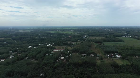 Aerial fly in shot of Cu Chi, Vietnam with farms, forests on sunny day with blue sky. alt