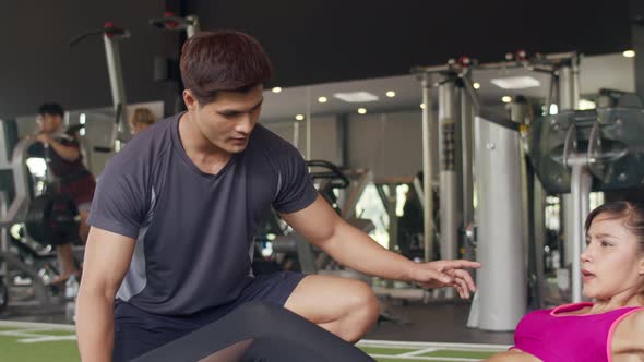 Handsome asian guy personal trainer focus body weight training to lady customer.