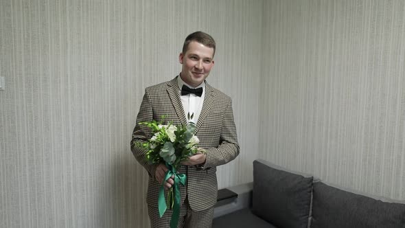 Groom with Wedding Bouquet in His Hands at Home. White Shirt, Jacket alt