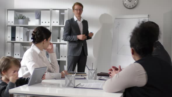 Businessman Giving Presentation while Kid Playing on Tablet alt