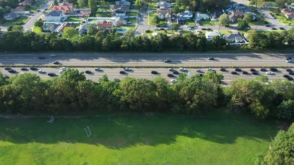 An aerial view of a parkway in the evening at rush hour. The camera truck left over a park while vie alt