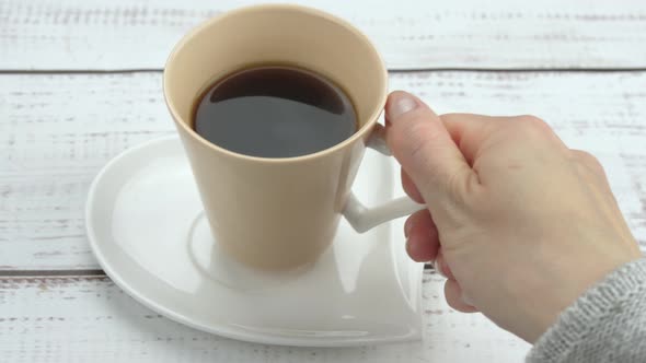 Female Hand Closeup Takes a Cup of Coffee While Enjoying a Hot Drink alt