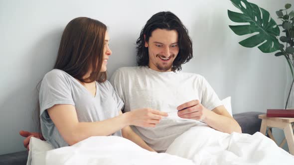 Cheerful Pregnant Wife Giving Husband Positive Pregnancy Test in Bed ...