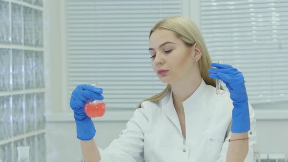 Young Blonde Girl In White Lab Coat Working In The Lab. Science Lab And Scientists Working