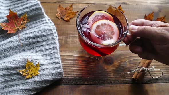 Putting a cup of tea with lemon on table with autumn decoration  slow motion