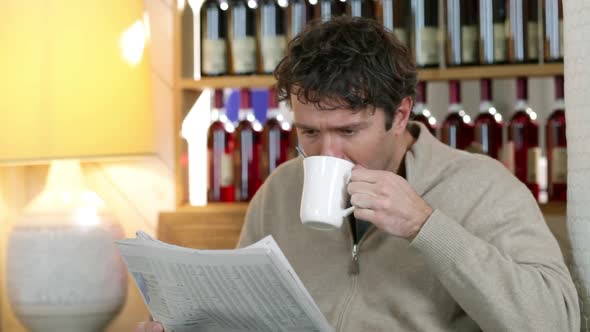 Man reading newspaper in cafe, drinking coffee alt
