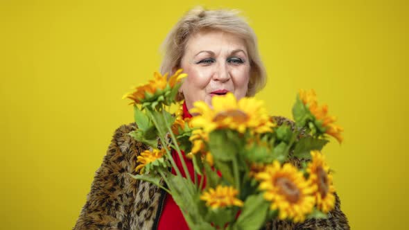 Excited Senior Woman Holding Bouquet of Sunflowers and Smiling Looking at Camera alt