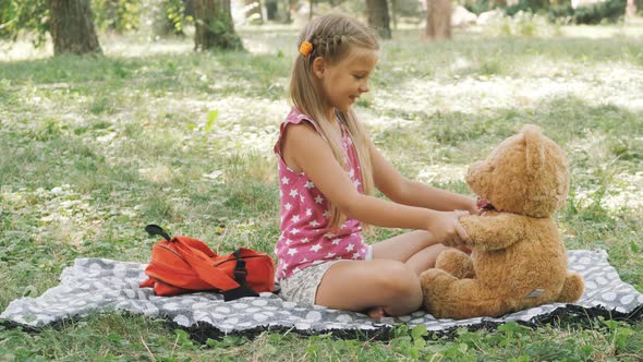 Happy little girl walking the park. Playing with a teddy bear in nature. Happy childhood. alt