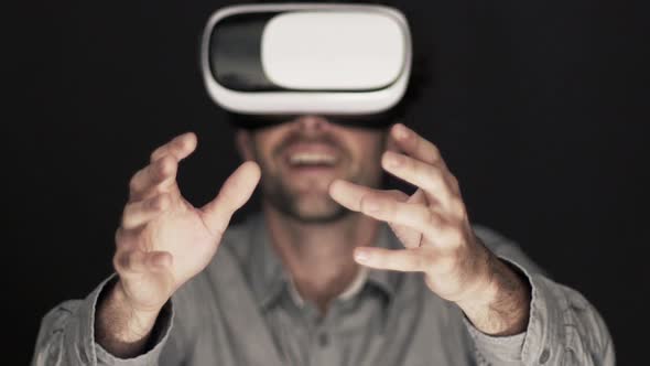 Slow motion shot of man reaching with hands while using virtual reality simulator alt