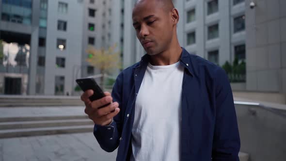 Ethnic Man Using Smartphone on Street alt