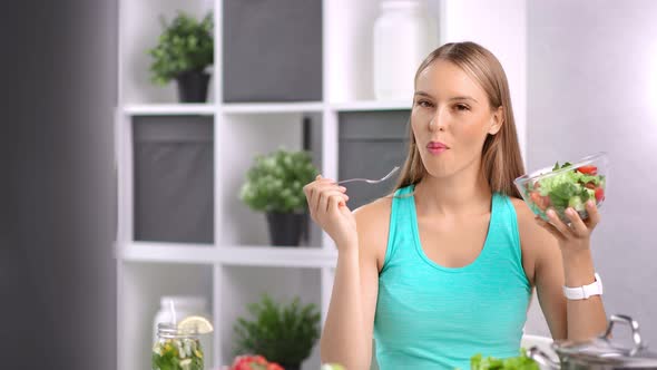 Attractive Dieting Girl Eating Fresh Organic Vegetable Salad in Kitchen at Home Looking at Camera alt