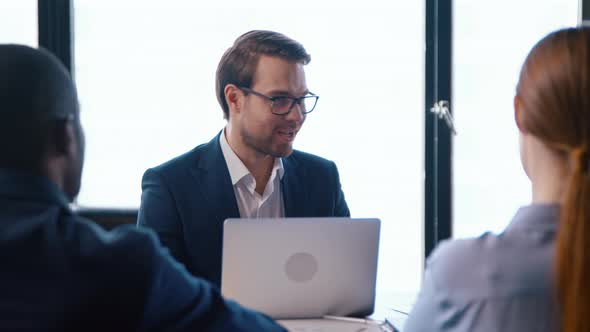 Handshake of young professional in a team to a business partner while sitting at a table alt