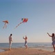 A Happy Young Family with a Child Play Kites Together on the Beach - VideoHive Item for Sale
