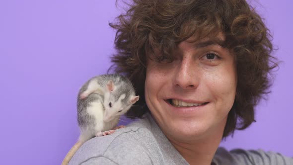 A Man with Curly Hair with a Pet Ratmouse on an Isolated Background in the Studio