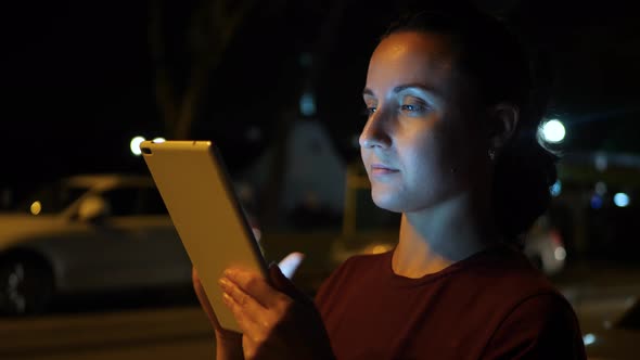 A Woman Uses a Tablet in a City Night. Technology, Communication and Navigation. alt