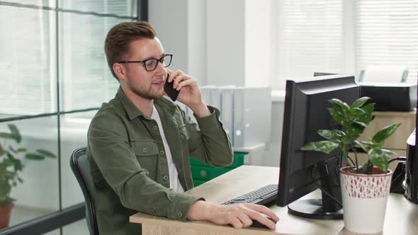 Portrait of Handsome Young Man in Glasses for Vision Talking on Mobile Phone While Sitting at alt