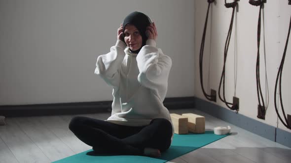 Muslim Woman Puts Headphones on Her Head alt