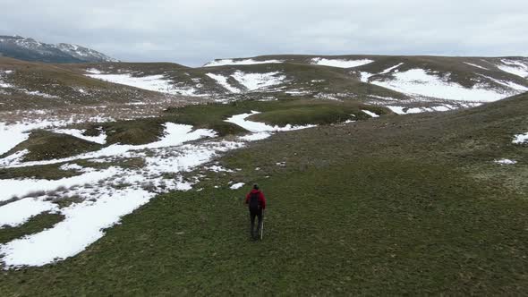 Aerial View of Wild Hillsides Covered with Snow in Places with Green Grass in Places Along Which a