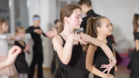 Concentrated Caucasian Girl Rehearsing Latin Ballroom Dance Movements with Classmates in Dancing alt