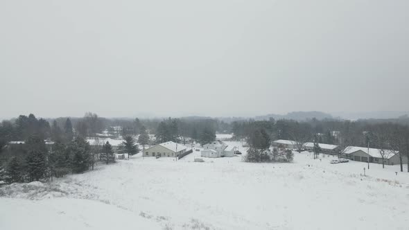 Drone view backing away from rural housing development nestled into the forest.