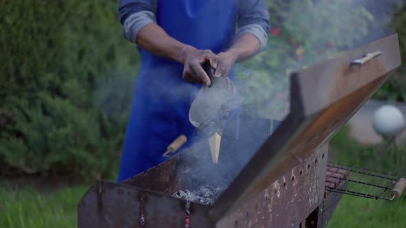 Unrecognizable African American Young Man in Apron Blowing Bbq Smoke Outdoors on Summer Day alt