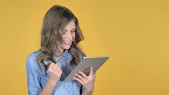 Young Girl Excited for Success While Using Tablet Isolated on Yellow Background alt