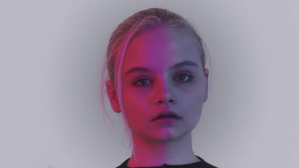 Young Blonde Pretty Woman Turning Around and Looking in the Camera in Red Lighting alt