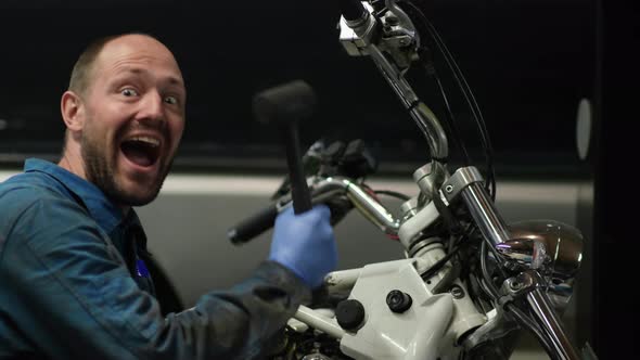 guy mechanic in blue overalls next to a motorcycle