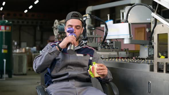 A young factory worker is enjoying lunch. Lunch break at work alt