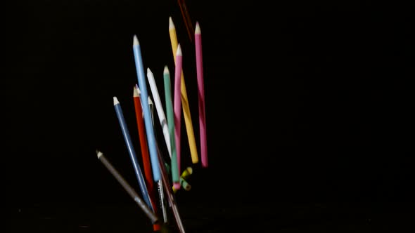 Colorful pencils falling on a black surface, Ultra Slow Motion alt