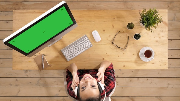 Young pretty woman listening to music at her working place alt