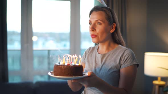 Happy Excited Woman Making Cherished Wish and Blowing Candles on Holiday Cake Celebrating Birthday alt
