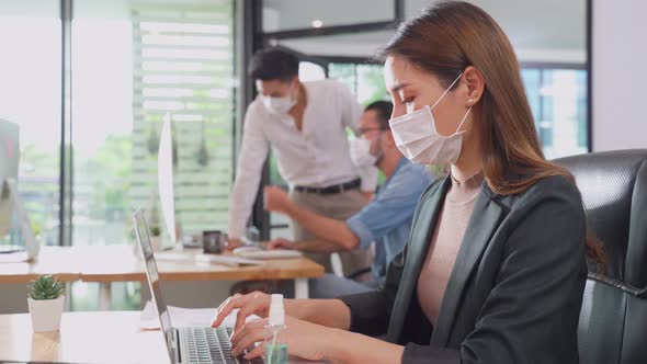 Group of Asian team business people working in office with new normal social distancing lifestyle. alt