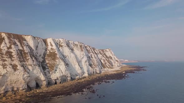 Drone flies low towards the White Cliffs of Dover with beautiful turquoise sea in the foreground. alt