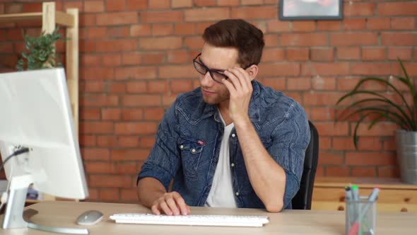 Front View of Happy Young Business Man Working Typing on Computer Taking Incoming Call on Mobile