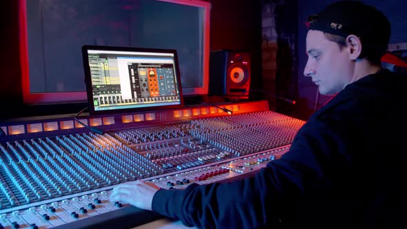 Stylish Audio Engineer Producer Working in Music Recording Studio Uses Mixing Board