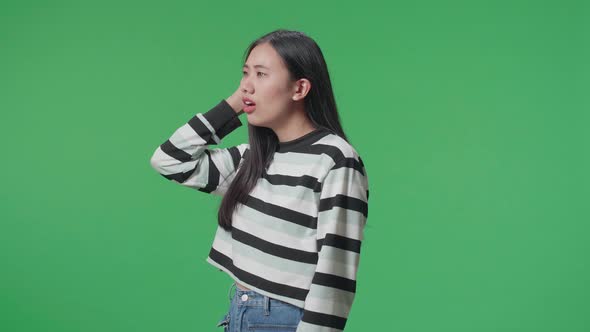 Side View Of A Puzzled Asian Woman Is Standing In Front Of Green Screen Background alt