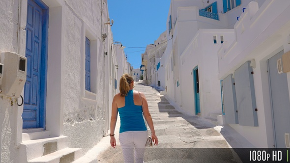 Following a Female Tourist Walking on a Narrow Greek Island Street alt