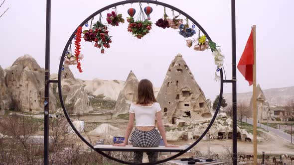 Lonely Young Caucasian Woman Sits On Fower Decorated Bench and Looking to StonE Valley in Cappadocia alt