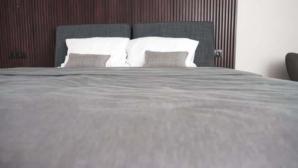 Modern double bed made up with clean white pillows and grey blanket alt