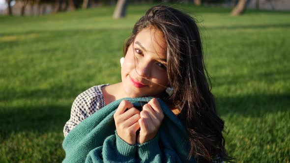 An attractive young hispanic woman trying to get warm and cozy with her sweater in cold windy weathe alt