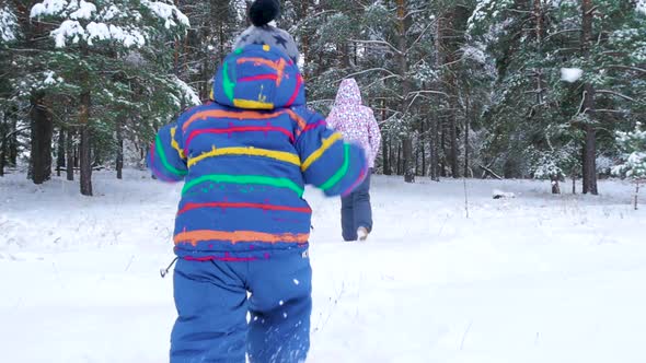 A Small Child Runs After His Mother Through a Snowy Forest or a Park on a Cold Winter Day alt