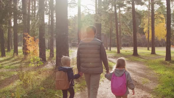 Father and Children Taking Stroll through Forest alt