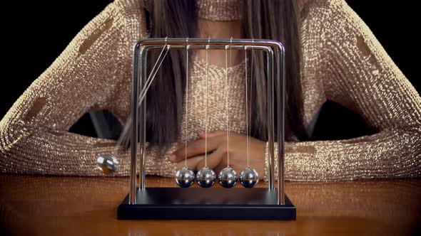 Woman Playing With A Newton's Cradle alt