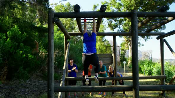 Friends applauding woman while exercising on monkey bar alt