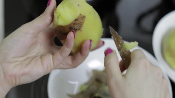 Female Housewife Hands Peeling Potatoes in the Kitchen. alt