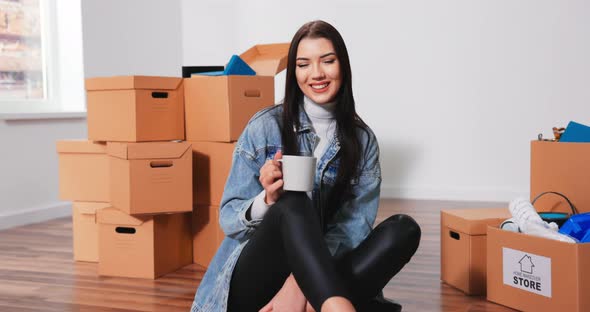 Cheerful Caucasian Woman Sitting on Floor Living Room with Cup of Coffee and Thinking About alt